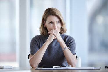 Pensive businesswoman looking away in conference room - CAIF13281