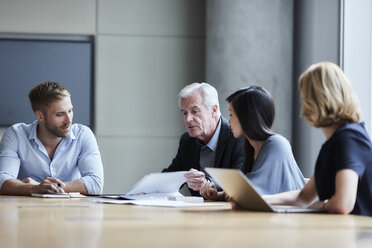 Business people discussing paperwork in conference room - CAIF13283