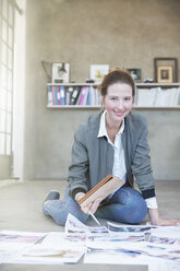 Portrait of young woman sitting on floor and working - CAIF13290