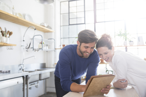 Young couple leaning at kitchen counter and looking at documents stock photo