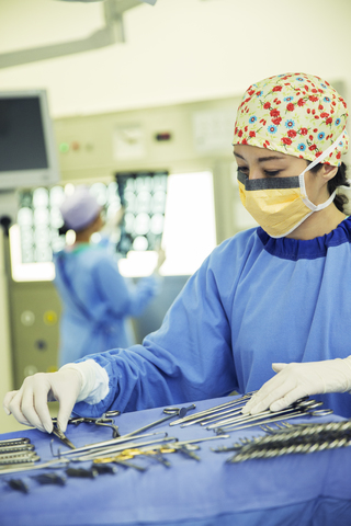 Chirurg ordnet chirurgische Scheren auf einem Tablett im Operationssaal an, lizenzfreies Stockfoto