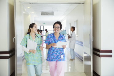 Lächelnde Krankenschwestern im Gespräch auf dem Krankenhausflur - CAIF13326