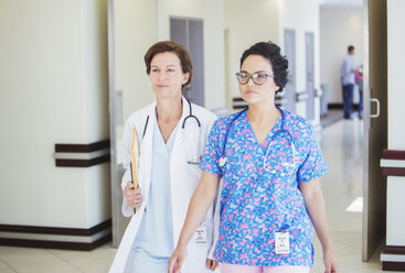Arzt und Krankenschwester gehen zusammen im Krankenhauskorridor - CAIF13340