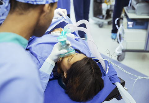 Anästhesist hält Sauerstoffmaske über das Gesicht des Patienten im Operationssaal, lizenzfreies Stockfoto