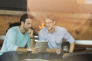 Männer trinken Rotwein und benutzen ein digitales Tablet - CAIF13383