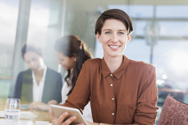 Porträt einer lächelnden Geschäftsfrau mit digitalem Tablet im Büro - CAIF13384