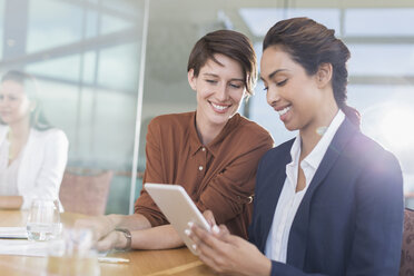 Lächelnde Geschäftsfrauen mit digitalem Tablet im Büro - CAIF13388