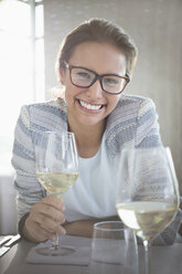 Porträt einer selbstbewussten Frau mit Brille, die Weißwein trinkt - CAIF13394