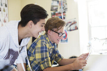 Zwei Jungen im Teenageralter haben Spaß bei der Verwendung eines digitalen Tablets im Zimmer - CAIF13421