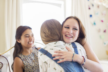 Three teenage girls embracing in bedroom - CAIF13439