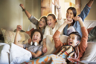 Gruppe von Teenagern, die auf dem Sofa fernsehen und Spaß haben - CAIF13440