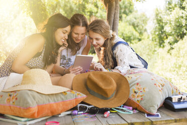 Three teenage girls using digital tablet in tree house - CAIF13442