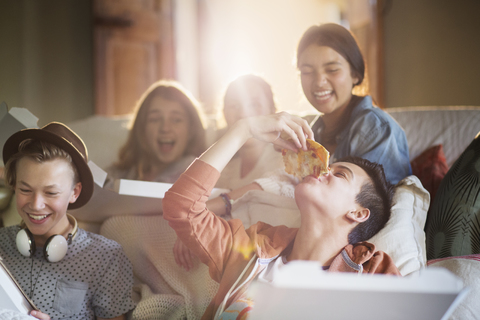 Gruppe von Teenagern beim Pizzaessen auf dem Sofa im Wohnzimmer, lizenzfreies Stockfoto