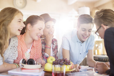 Eine Gruppe lächelnder Teenager versammelt sich um einen Tisch im Esszimmer - CAIF13455