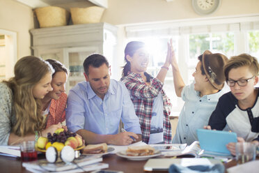 Teenagers with mid adult man sitting at table in dining room - CAIF13467