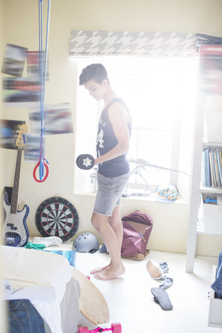 Jugendlicher trainiert mit stummer Glocke in seinem Zimmer, lizenzfreies Stockfoto