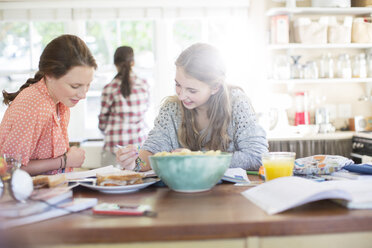 Teenage girls learning at table in kitchen - CAIF13475