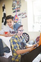 Two teenage boys using electronic devices in room - CAIF13476