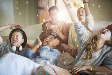 Gruppe von Teenagern, die auf dem Sofa Popcorn auf sich werfen - CAIF13483