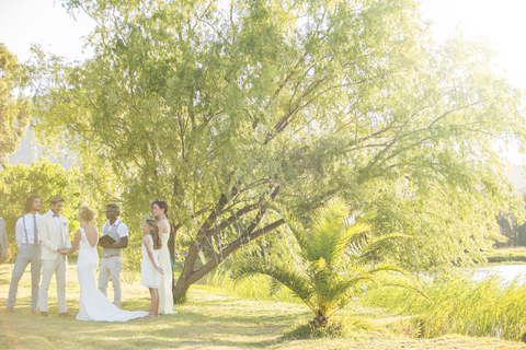 Junges Paar und ihre Gäste stehen im Garten bei der Hochzeitszeremonie, lizenzfreies Stockfoto