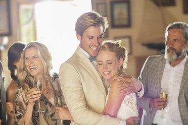 Junges Paar und Gäste beim Hochzeitsempfang in einem Hauswirtschaftsraum - CAIF13522