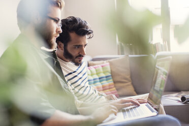 Lässige Geschäftsleute arbeiten am Laptop auf dem Sofa im Büro - CAIF13575