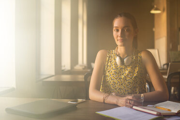 Portrait casual businesswoman with headphones working in office - CAIF13577