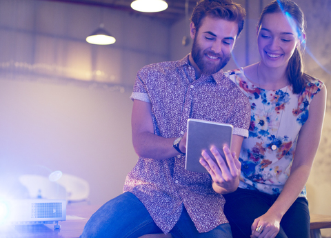 Lässiger Geschäftsmann und Geschäftsfrau teilen sich ein digitales Tablet im Büro, lizenzfreies Stockfoto