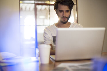 Casual businessman working at laptop in conference room - CAIF13599