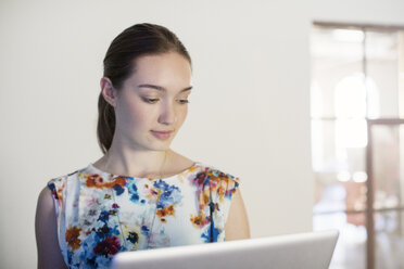 Businesswoman working at laptop in office - CAIF13601