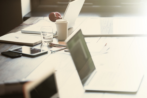 Laptops, digital tablet and paperwork on table in sunny office stock photo