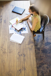 Kreative Geschäftsfrau, die am Tisch im Büro in ein Notizbuch schreibt - CAIF13611