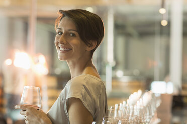 Porträt einer lächelnden Frau bei einer Weinprobe in einem Weinkeller - CAIF13651