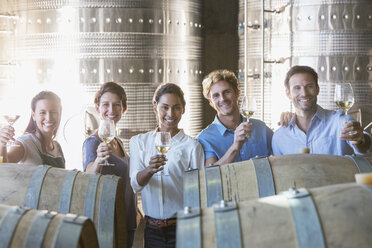Portrait smiling winery employees barrel tasting in cellar - CAIF13669