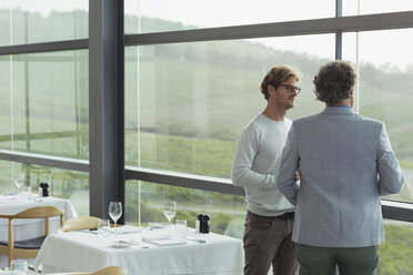 Männer unterhalten sich am Fenster des Speisesaals einer Weinkellerei - CAIF13677