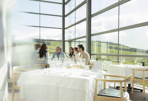 Freunde sitzen am Tisch im sonnigen Speisesaal des Weinguts - CAIF13691