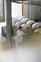 Winzer im Laborkittel bei der Untersuchung von Weißwein im Weinkeller - CAIF13693