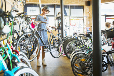 Woman selecting bicycle from rack in bicycle shop - CAIF13713