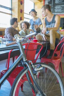 Freunde hängen im Café hinter dem Fahrrad ab - CAIF13718