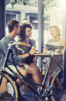 Freunde hängen am Kaffeetisch hinter dem Fahrrad ab - CAIF13723