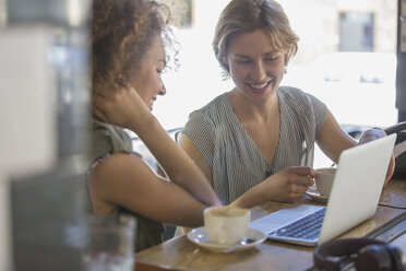 Geschäftsfrauen mit Kaffee, die in einem Café am Laptop arbeiten - CAIF13742