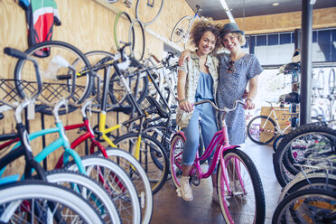 Porträt lächelnde Frauen umarmen mit Fahrrad in Fahrradladen - CAIF13745