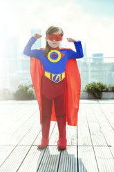 Superheldenmädchen, das auf dem Dach der Stadt seine Muskeln spielen lässt - CAIF13755