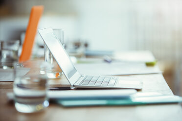 Office supplies, laptop and glass of water on desk in office - CAIF13816