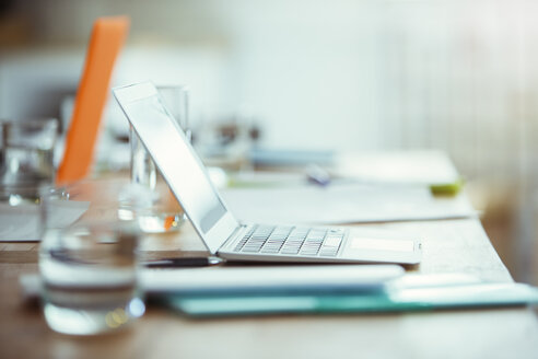 Büromaterial, Laptop und ein Glas Wasser auf dem Schreibtisch im Büro - CAIF13816