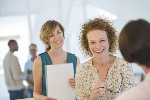 Büroangestellte plaudern und lachen während einer Besprechung, lizenzfreies Stockfoto