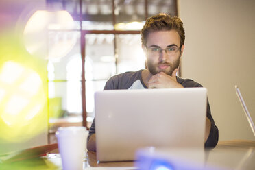 Konzentrierter Geschäftsmann bei der Arbeit am Laptop im Büro - CAIF13864