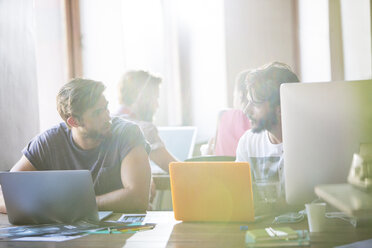 Kreative Geschäftsleute, die an Laptops arbeiten und sich im Büro unterhalten - CAIF13886