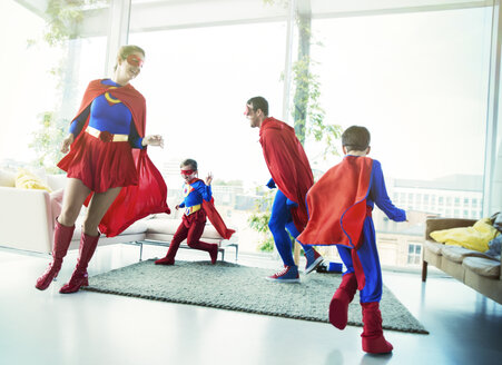 Superheldenfamilie, die sich gegenseitig im Wohnzimmer jagt - CAIF13941