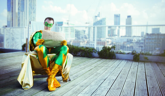 Superheld liest Zeitung auf dem Dach der Stadt - CAIF13945